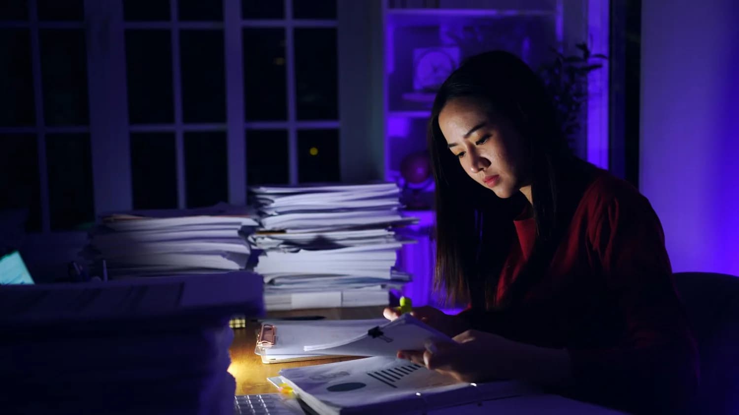 Analyst reviewing operational reports late into the evening at a capability center desk